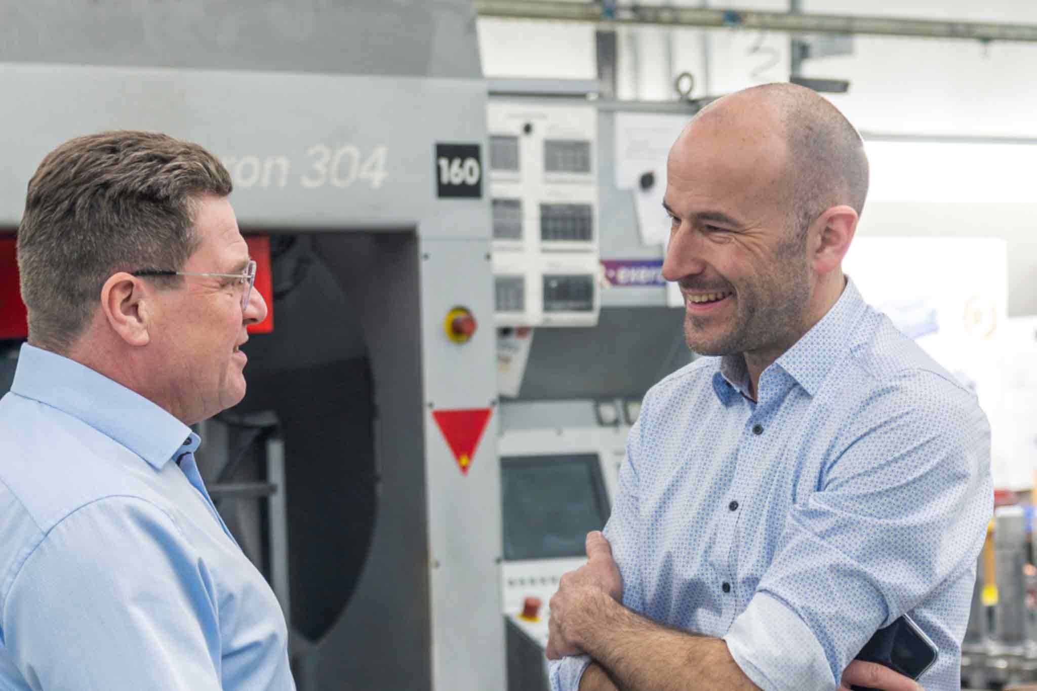 MAPAL consultant Alfred Baur talks to Managing Director Dr. Jens Buchert. You are standing in front of a machining centre.