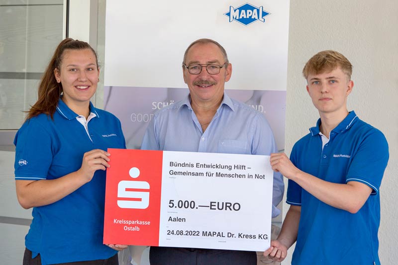 Chairman of the Works Council Uwe Homann (centre) with two trainees and the symbolic cheque