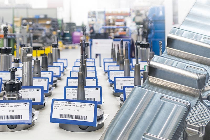 Gerüstete Werkzeuge stehen in der Fertigung. Sie sind in mehreren Reihen angeordnet und mit Label versehen. Im Vordergrund eine komplexe Form von Walter Formenbau.