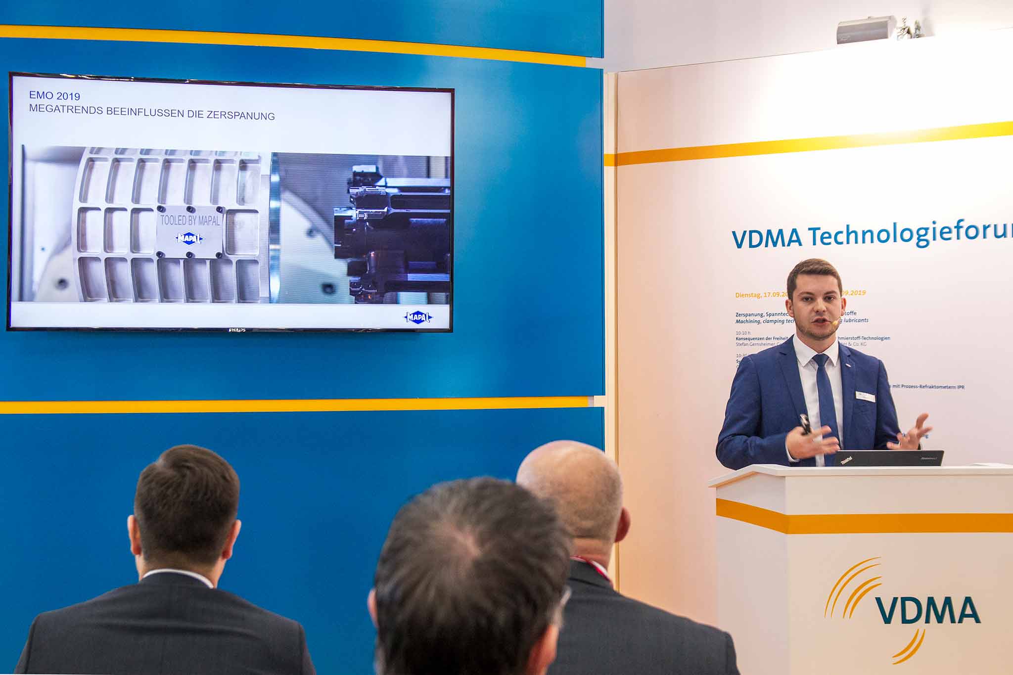 Dennis Minder spricht beim VDMA-Technologieforum. Er ist rechts im Bild, links wird groß seine Präsentation angezeigt.