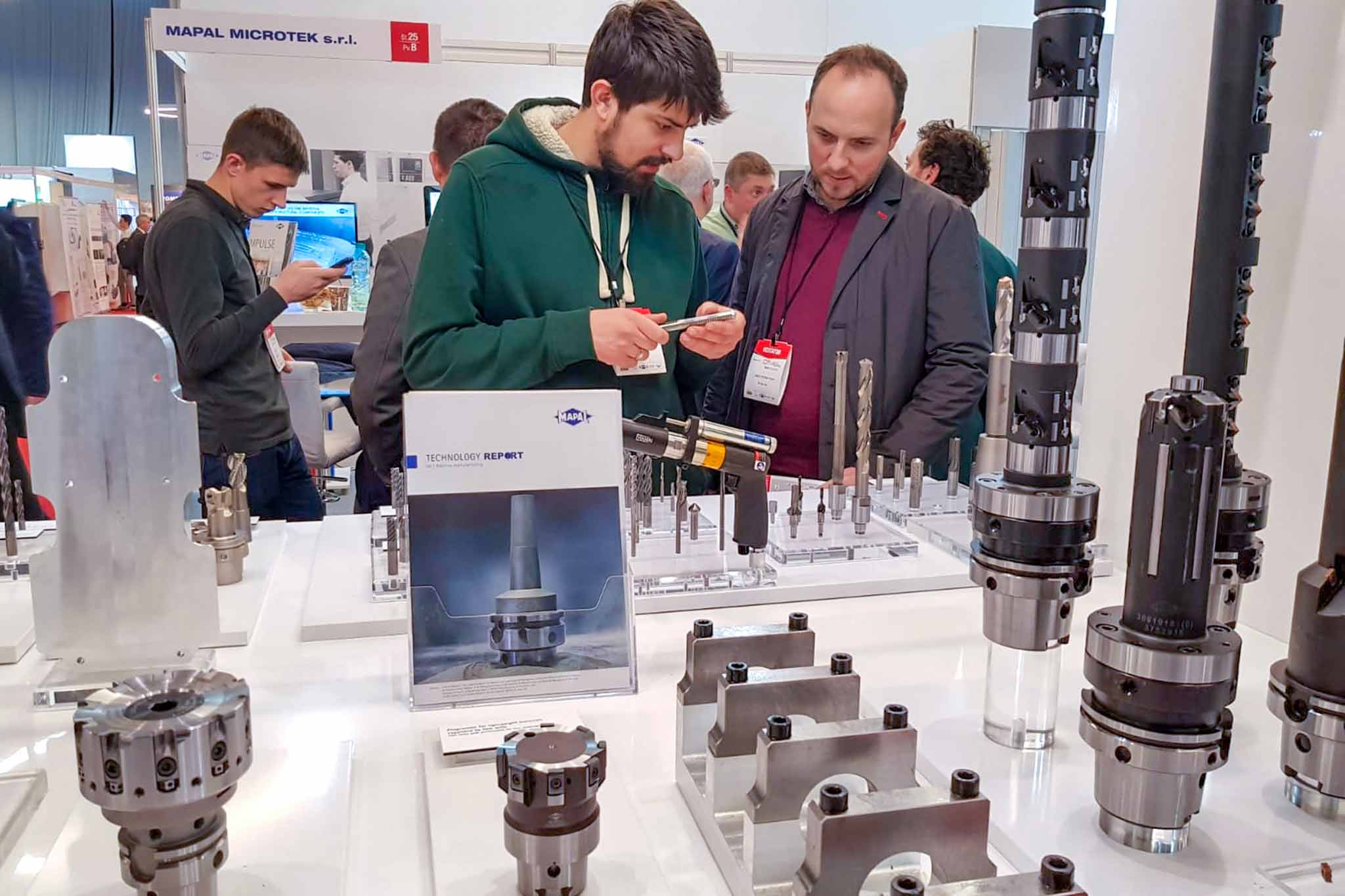 Two trade fair visitors look on with interest at a tool on the MAPAL exhibition stand.