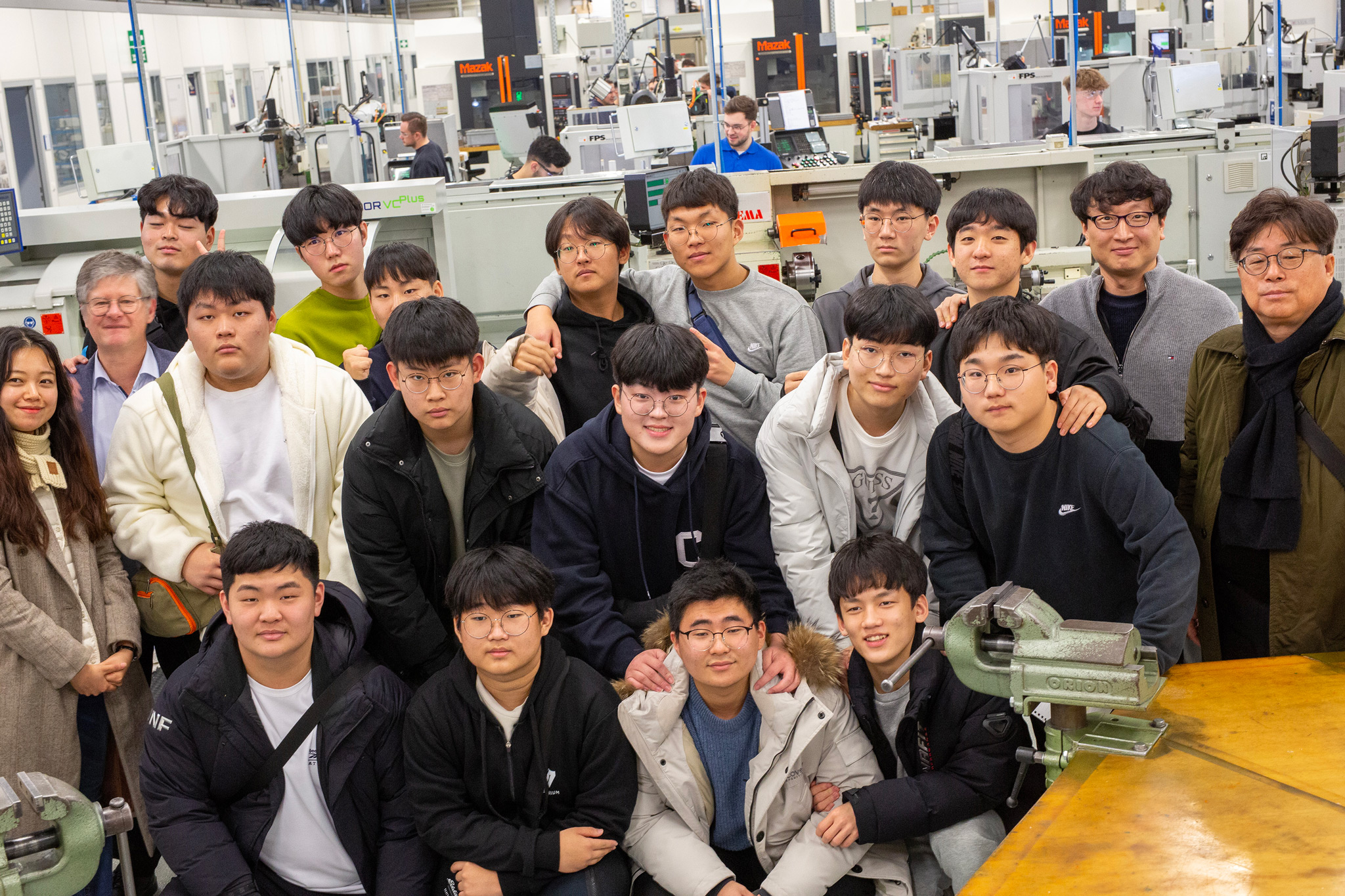 Auf dem Bild ist eine Schülergruppe aus Südkorea mit ihren Lehrkräften im Ausbildungszentrum von MAPAL zu sehen.