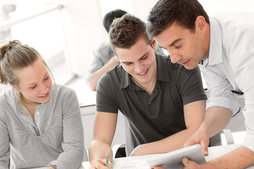 An employee explains a business process to two students.