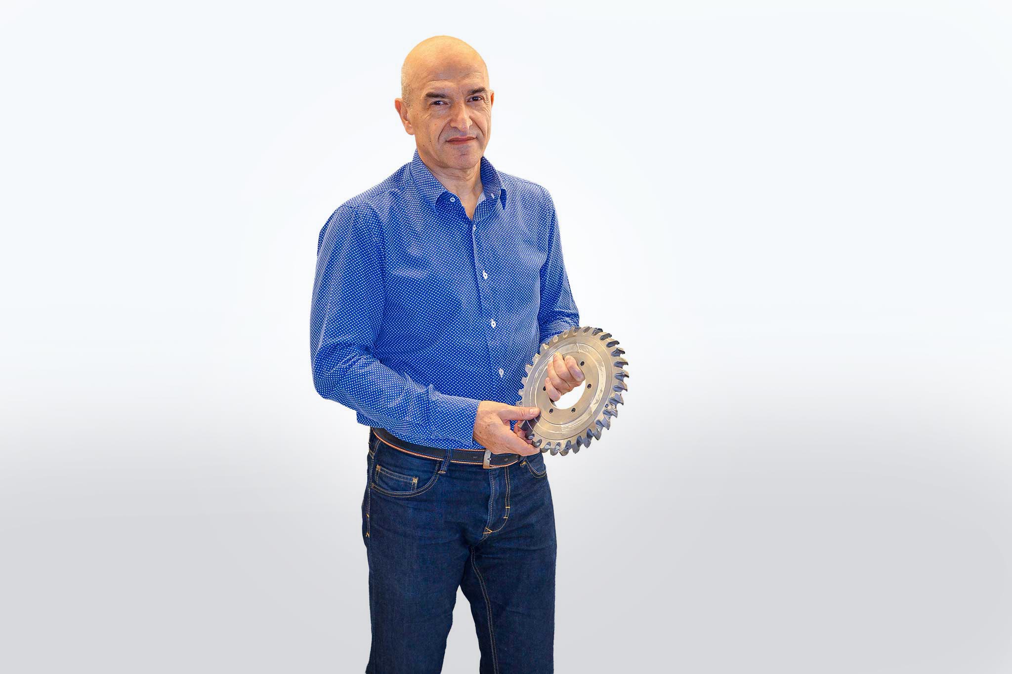 Valentin Andrei against a white background holding a large tool. 