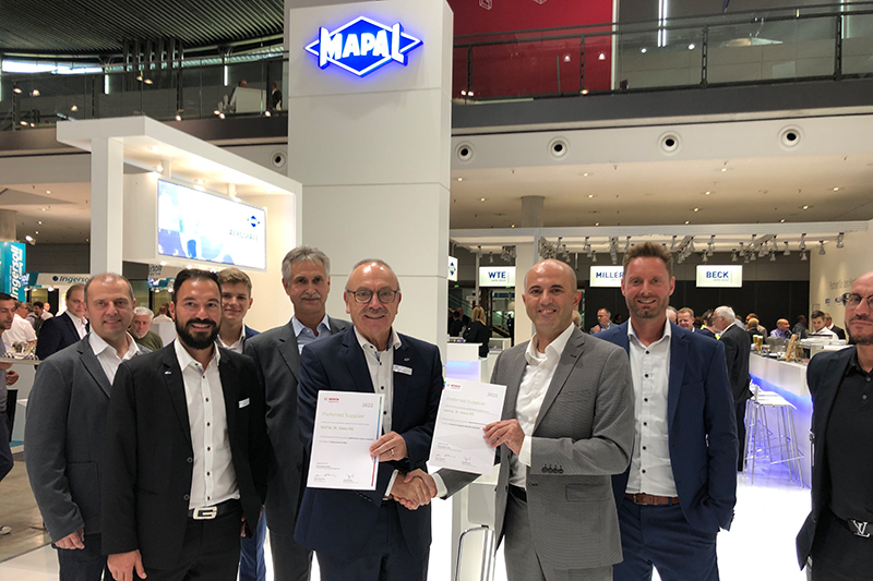On the trade fair stand at AMB. Batu Ulucay from Bosch presents the Supplier Awards 2021 und 2022 to the MAPAL team.