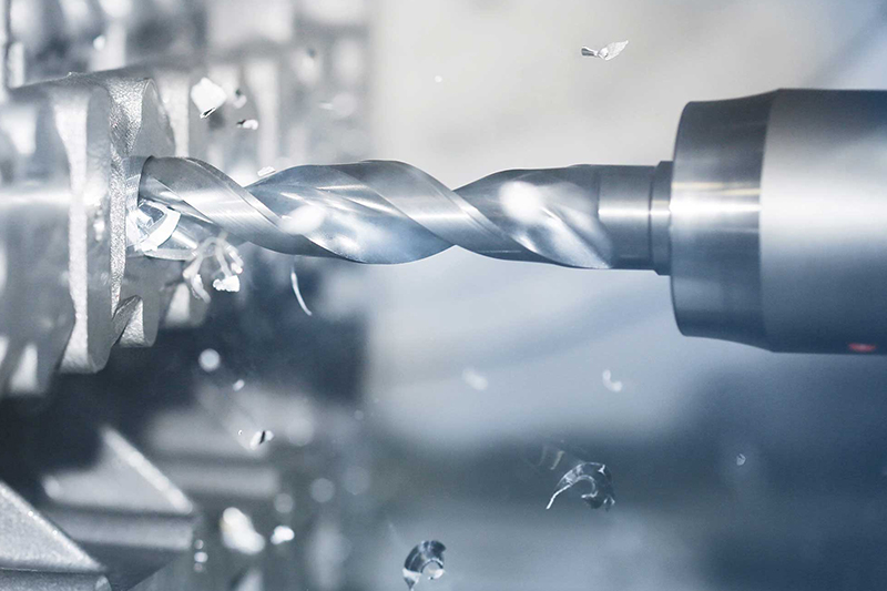 A drill during the machining of a workpiece. There are flying chips.