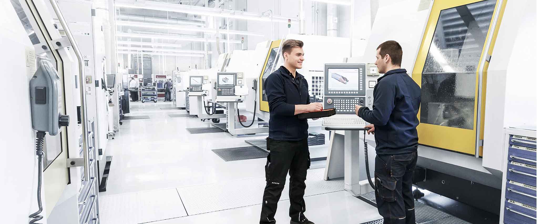 Two MAPAL employees are having a technical discussion in production.