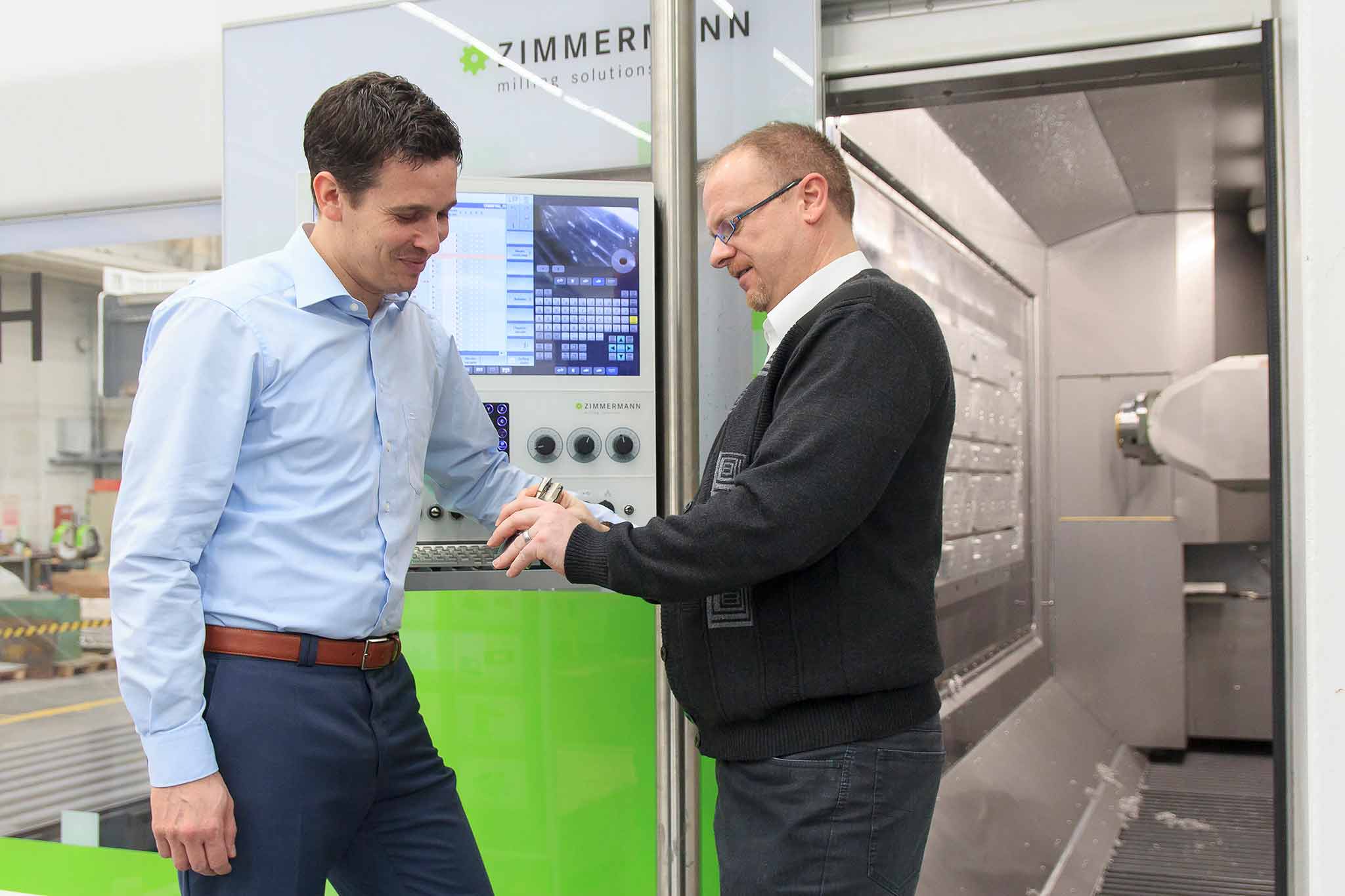 Dietmar Maichel and Steffen Nüssles stand in front of the horizontal machining centre FZH and talk to one another. 