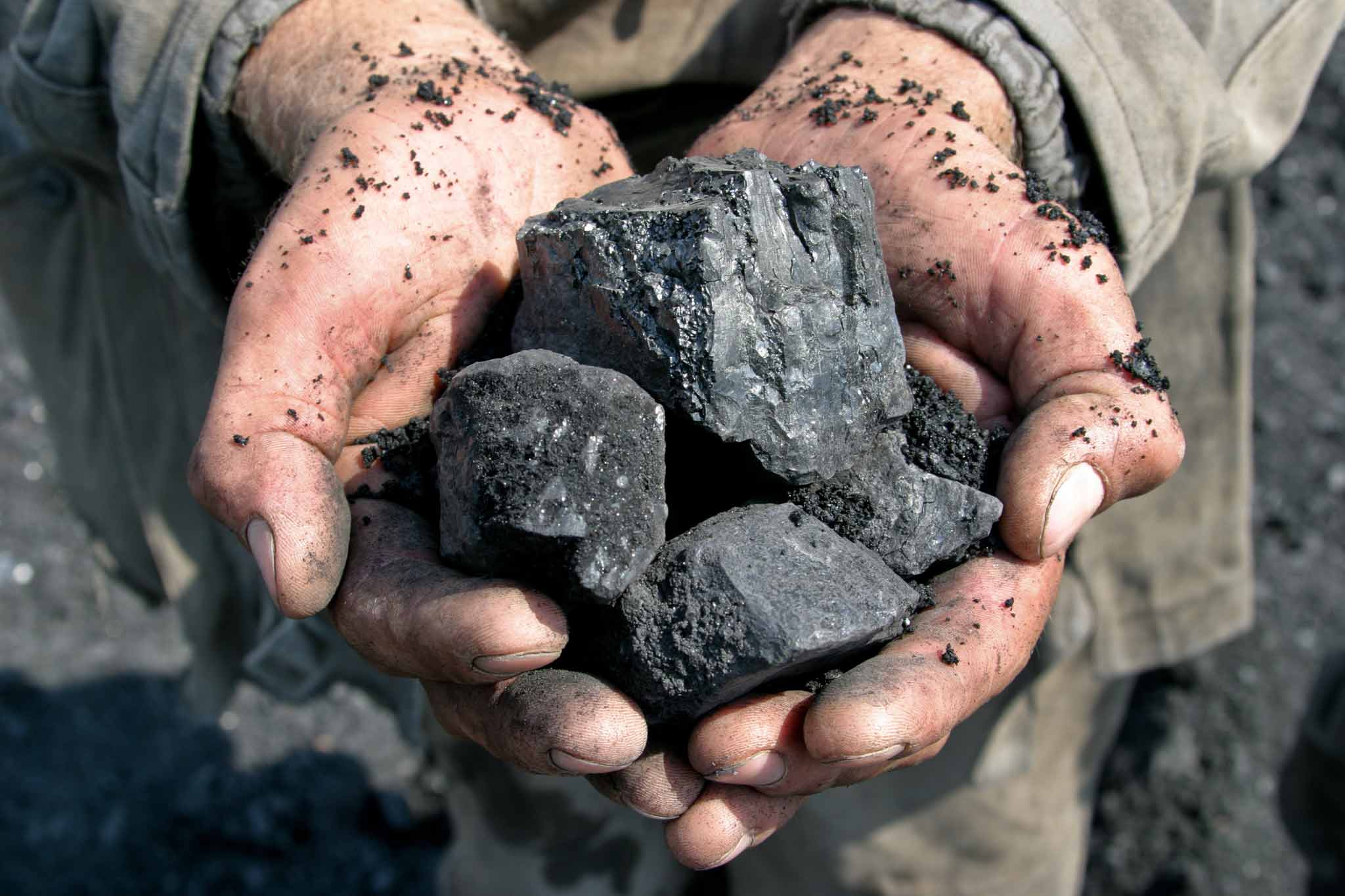Das Bild zeigt zwei Hände, die Gestein aus dem Bergbau halten.