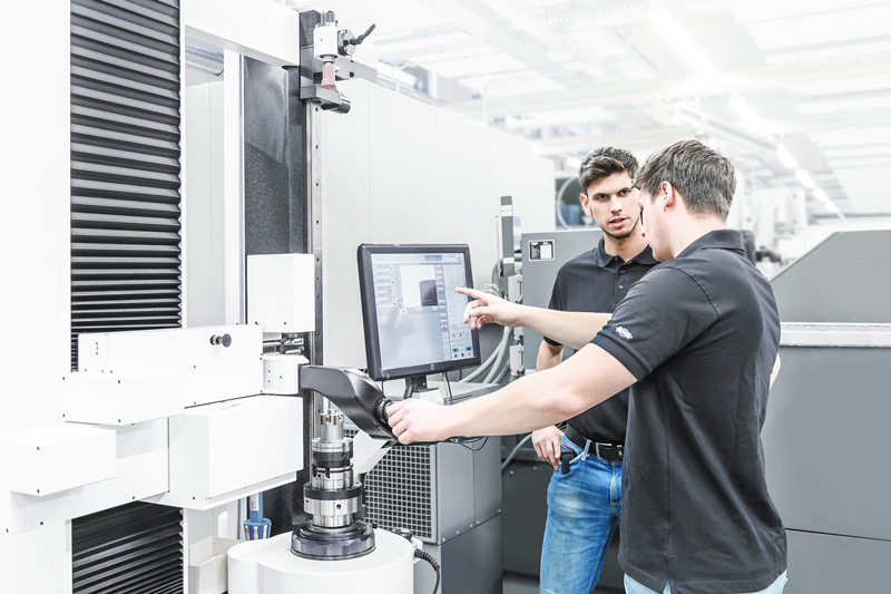 Two engineers in conversation. They are standing in front of the terminal of a setting device for tools.