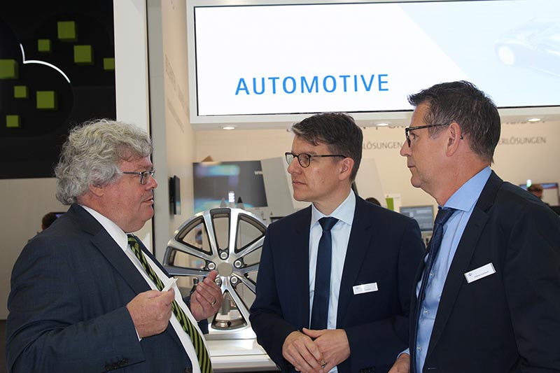 Reinhard Bütikofer having a conversation with Dr Jochen Kress and Andreas Enzenbach in front of the exhibition stand automotive presenter.