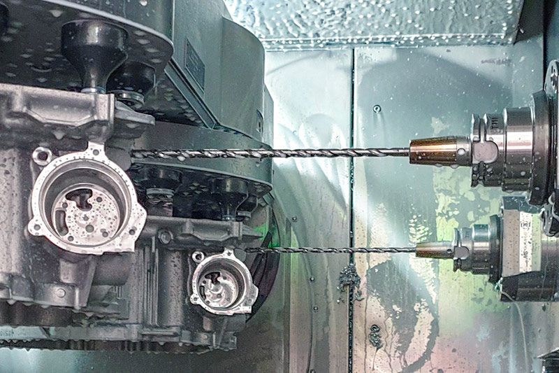 Un regard à l'intérieur de la machine montre deux forets profonds en PCD de MAPAL usinant des carters d’embrayage sur des machines à double broche.