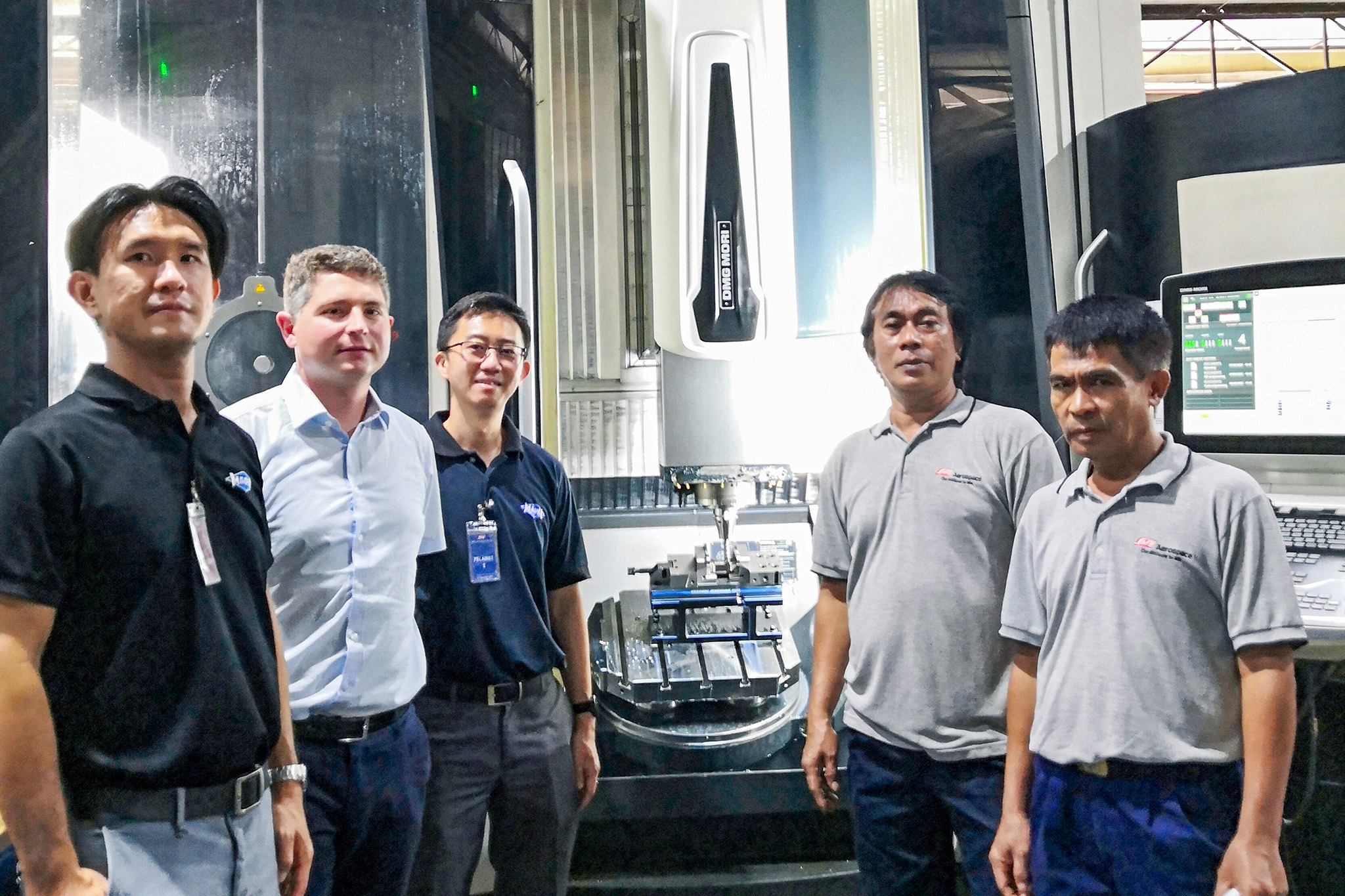 Fünf Mitarbeiter von SMEA und MAPAL stehen vor einer Maschine.