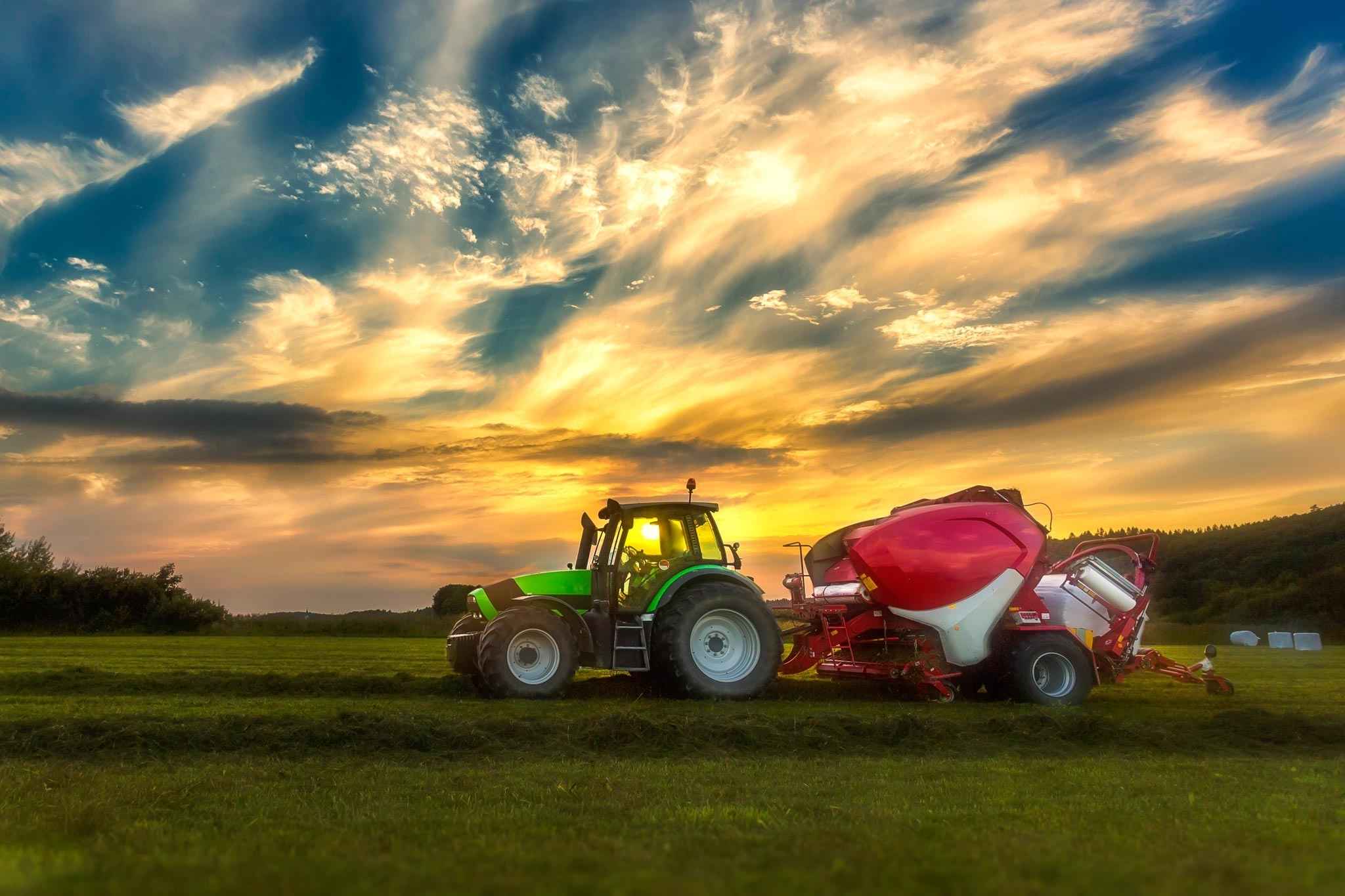 Schlepper mit Ballenpresse bei der Arbeit auf dem Feld.