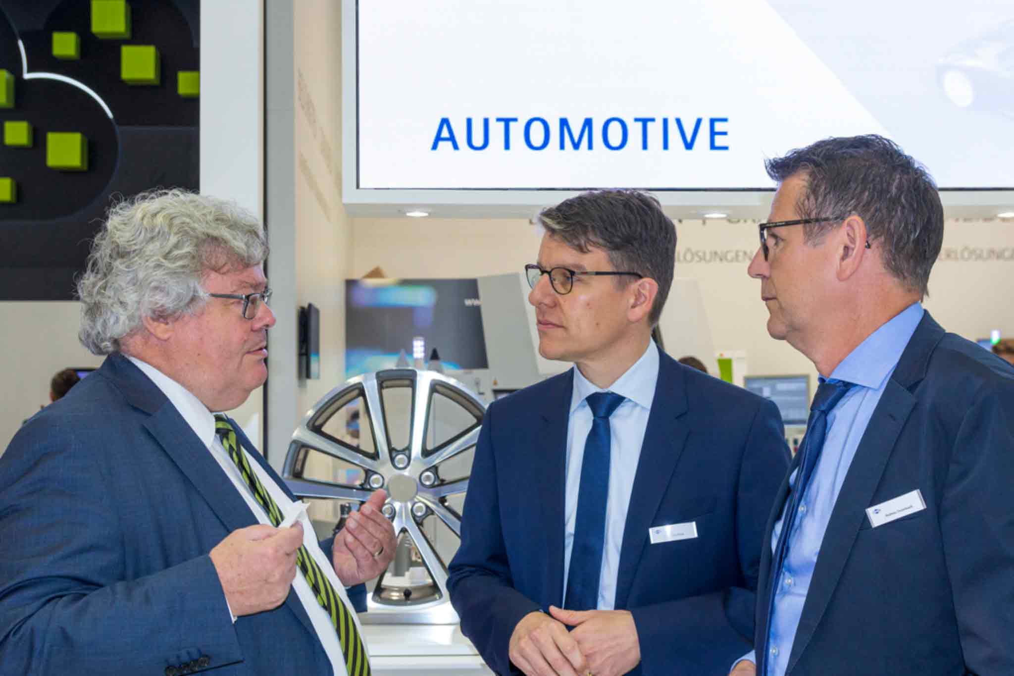 Reinhard Bütikofer having a conversation with Dr Jochen Kress and Andreas Enzenbach in front of the exhibition stand automotive presenter.