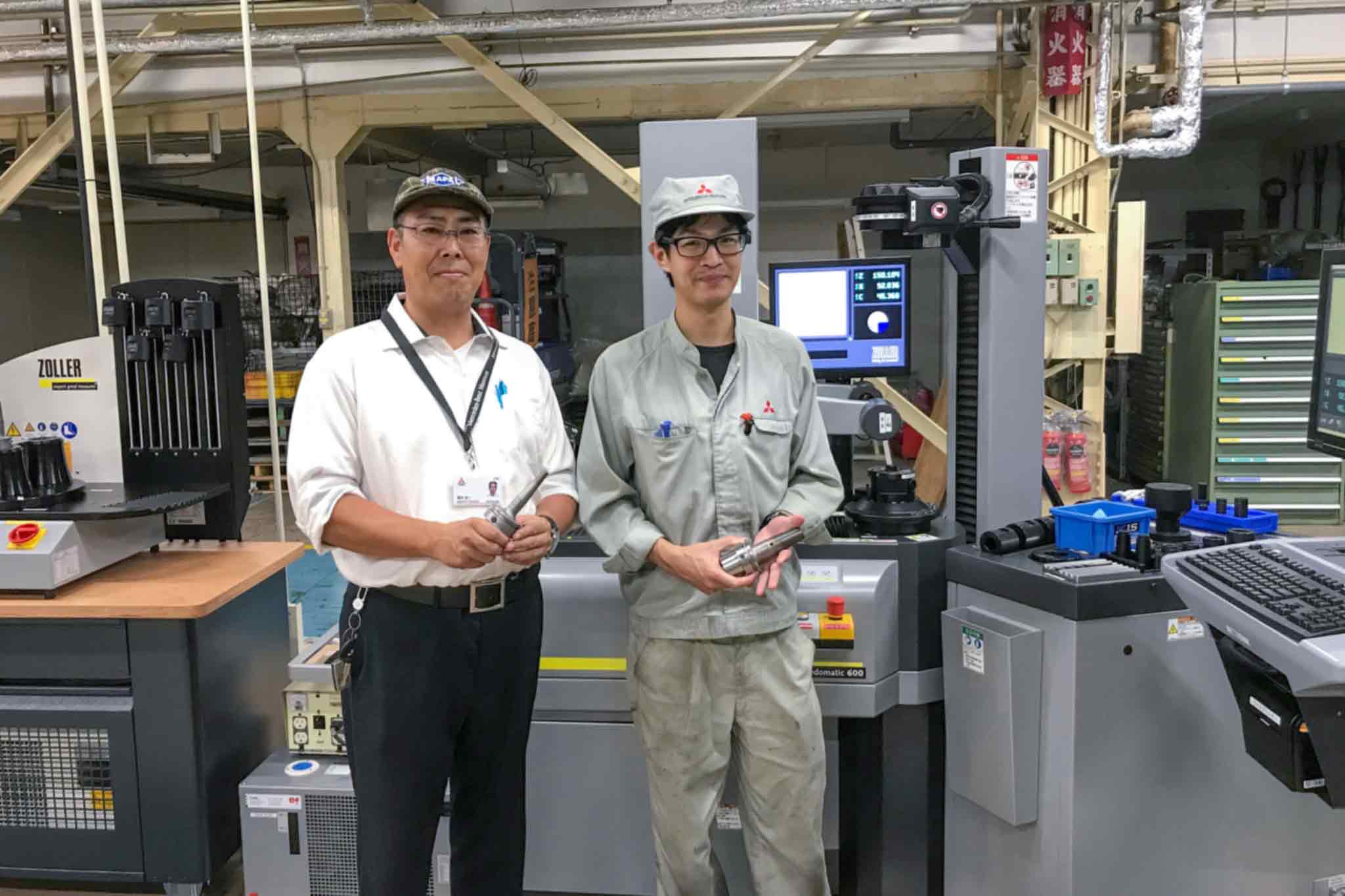 Naoto Katayama and Koichi Fukui are in the manufacturing area. Both hold a shrink chuck in their hands.